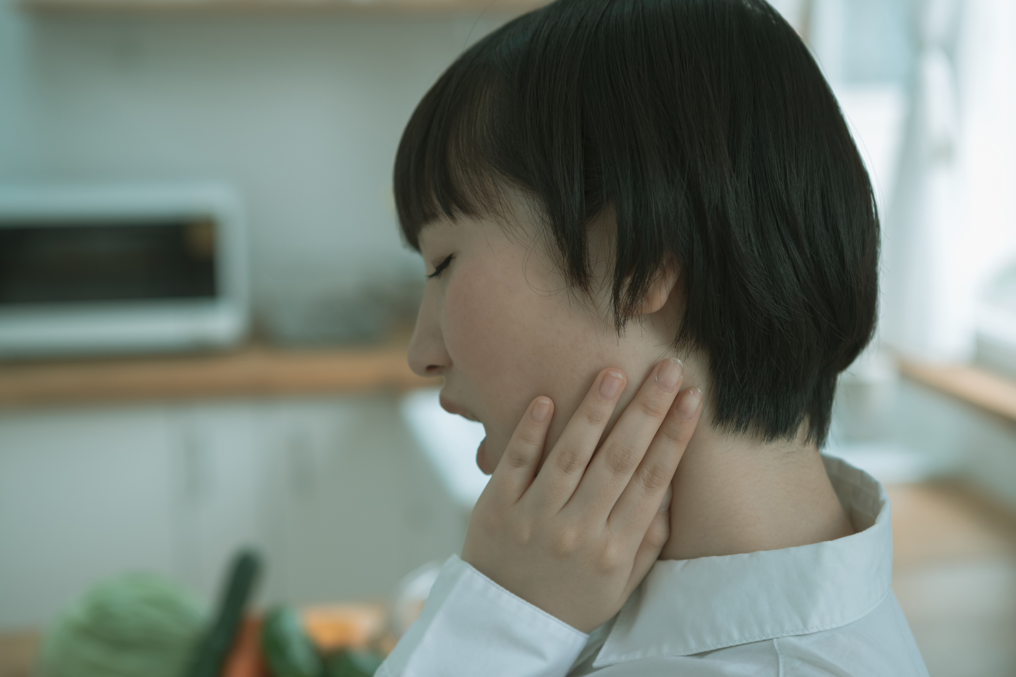 顎に違和感を感じる女性│瀬戸市で親知らず治療なら、瀬戸歯科